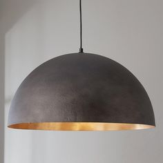 a gray and gold colored light hanging from a ceiling fixture in a white walled room