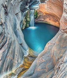 an image of a waterfall in the middle of a mountain with blue water and rocks