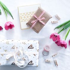 a present wrapped in brown paper next to pink tulips