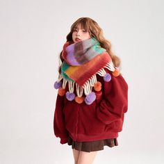 a woman in a red jacket and multicolored pom - pom scarf