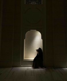 a woman sitting on the floor in front of a doorway at night with her head down