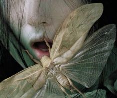 a close up of a person with a moth on their shoulder and mouth open to the camera