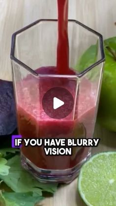 a blender filled with red liquid sitting on top of a table next to an apple