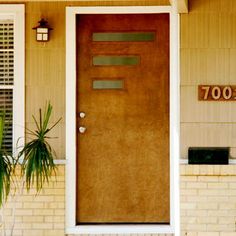 a brown front door with two planters on either side and the number 7000