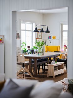 an open living room and dining area with white walls, wood flooring and yellow chairs