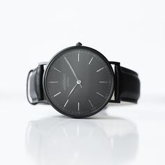 With this Minimalist Men's Watch, nothing gets in the way of him looking his sharpest. Only the finest materials are used to craft this beautiful minimalist watch, from the jet black genuine leather strap to the sandblasted gunmetal diamond-cut case. From eye-catching design to the precision quartz time-keeping mechanism, each detail elevates this minimalist watch, ensuring he'll always arrive in style and on time. This is also a gift that only you can give. The back of the Minimalist Men's Watch is the ideal space for a message, one you can have engraved in a modern font or with your own handwriting. Then to make this luxurious experience complete, he'll enjoy unboxing his new watch from its crisp, lavish box.  For a timepiece he's sure to love from the second he opens it, order his Minim Engraved Handwriting, Minimalist Men, Personalized Watches, Watch Engraving, Minimalist Watch, Stainless Steel Polish, Watch Companies, Modern Fonts, Less Is More