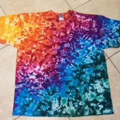 a tie dyed t - shirt is laying on the floor in front of a tile floor