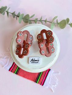 two decorated cookies sitting on top of a white plate next to a green leafy plant