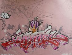 graffiti written on the side of a wall with pink and purple colors, including an image of a crown