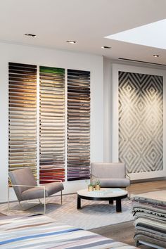 a living room filled with furniture and lots of windows covered in shades of different colors