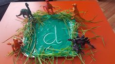 the cake is decorated with plastic dinosaurs and grass