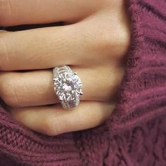 a woman's hand with a diamond ring on her finger, wearing a purple sweater