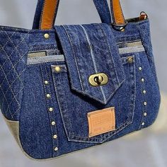 a purse made out of jeans with buttons on the front and side pockets, hanging from a hook