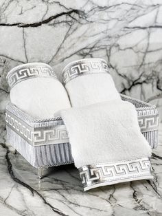 two white towels sitting on top of a chair in front of a marble countertop