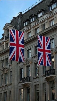 two union jack and british flag flags hanging in front of a large building with balconies