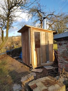 a small wooden shed sitting in the middle of a yard next to a brick wall