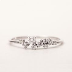 a white gold ring with three small diamonds on the top and one smaller diamond in the middle