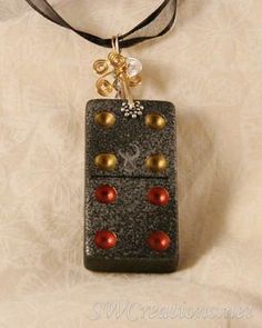 a black and gold necklace with red beads on it's side, hanging from a cord