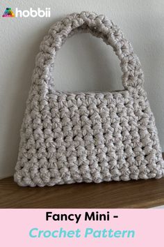 a crocheted purse sitting on top of a wooden table next to a white wall