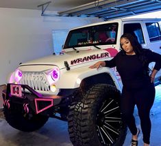 a woman standing next to a white jeep with pink lights on it's hood