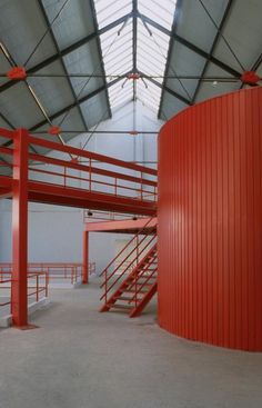 the inside of a building with red metal railings and stairs leading up to it