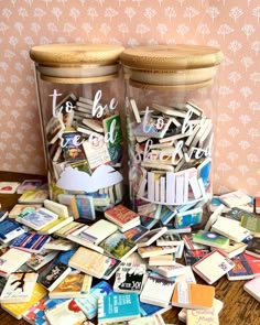 two glass jars filled with books on top of a table