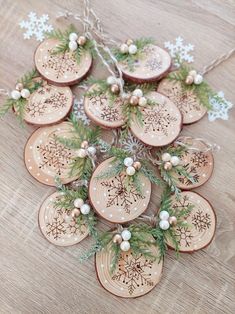 wooden ornaments are arranged on a table with pine branches and snowflakes hanging from them