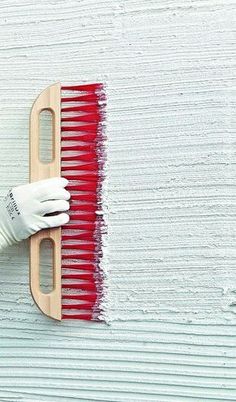 a person in white gloves is painting a wall with red paint on the side of it