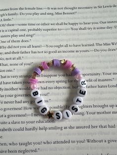 a beaded bracelet with words written in black and white on top of an open book