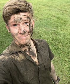 a young man with mud on his face holding a frisbee in the grass