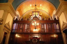 the inside of a church with wooden pews and chandeliers hanging from the ceiling