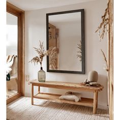 a wooden bench sitting under a mirror in a living room next to a vase filled with plants