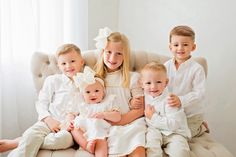 a group of young children sitting next to each other on top of a white couch