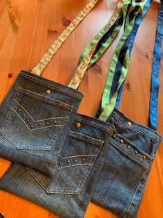 two pairs of jeans sitting on top of a wooden floor next to a tie holder