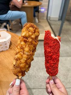 two people holding up food on sticks at a table