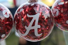 three glass ornaments with the letter a on each ornament are shown in red and white