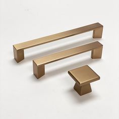 three brass - plated objects on a white background, including one bench and two stools