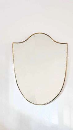 an oval mirror hanging on the wall with gold trimmings and a white background