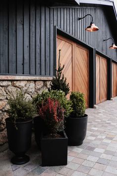 three black planters sitting next to each other on a brick floor near a building