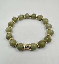 Olive green 10mm natural gemstones with gold tone accents, stretchy bracelet. Gold Beaded Bracelets With Jade Natural Stones, Gold Jade Beaded Bracelets With Natural Stones, Casual Gold Beaded Bracelets With Gemstone, Gold Jade Beaded Bracelets, Gold Stretch Bracelet With Natural Stones, Casual Green Stretch Bracelet With Natural Stones, Elegant Beaded Jade Stretch Bracelet, Elegant Round Jade Stretch Bracelet, Elegant Jade Stretch Bracelet