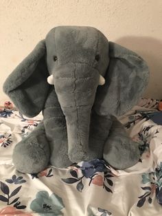 an elephant stuffed animal sitting on top of a bed