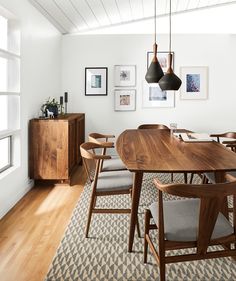 a dining room table and chairs in front of a window with pictures on the wall