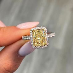 a woman's hand holding a fancy yellow diamond ring