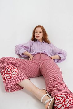 Elevate your wardrobe with our vibrant Rosas Embroidered Trousers. Made from hand-spun, handwoven cotton from West Bengal, these high waisted trousers are crafted with intricate detail. Featuring a striking red and white vichy pattern, the silhouette is accented with patch embroidered roses, and contrasting white stripes with piping. Product details Red and white vichy pattern Crafted from hand-spun and handwoven cotton sourced from West Bengal White piping on the sides and around the back pocke Traditional Red Bottoms For Spring, Embroidered Cotton Wide Leg Pants, Traditional Red Pants For Spring, Traditional Trousers For Spring, Red Cotton Bottoms With Floral Embroidery, Cotton Straight Pants With Floral Embroidery, Traditional Cotton Pants With Floral Embroidery, Traditional Floral Embroidered Cotton Pants, Casual Floral Embroidered Trousers