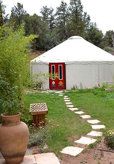 a white yurt in the middle of a field with a path leading to it