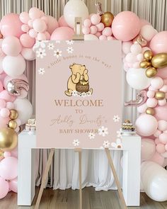 a welcome sign surrounded by balloons and streamers in pink, gold and white colors