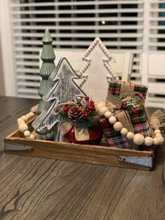 a wooden box filled with christmas decorations on top of a table next to a window