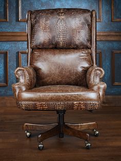 a brown leather office chair sitting on top of a wooden floor next to a blue wall