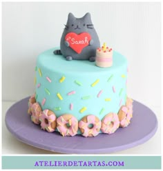 a cat cake with sprinkles and donuts on top is sitting on a purple plate