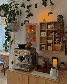 a coffee maker sitting on top of a wooden counter next to a potted plant